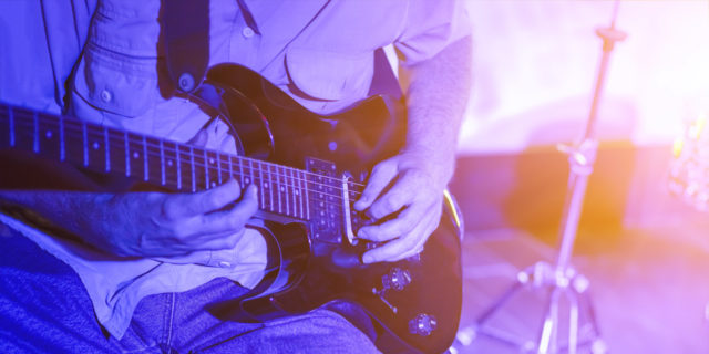 Closeup of person playing electric guitar on stage