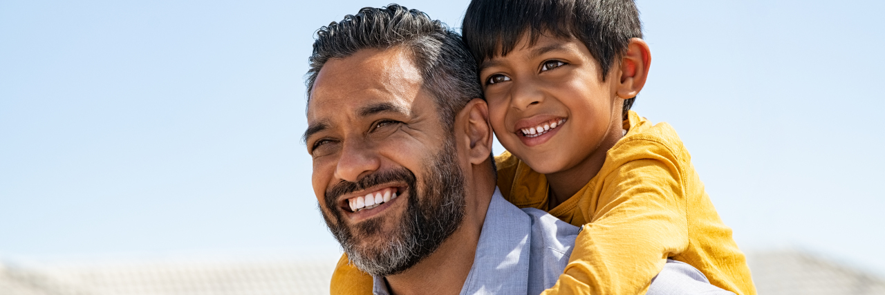 Smiling dad giving piggyback ride to son.