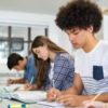 Diverse group of high school students writing in workbooks