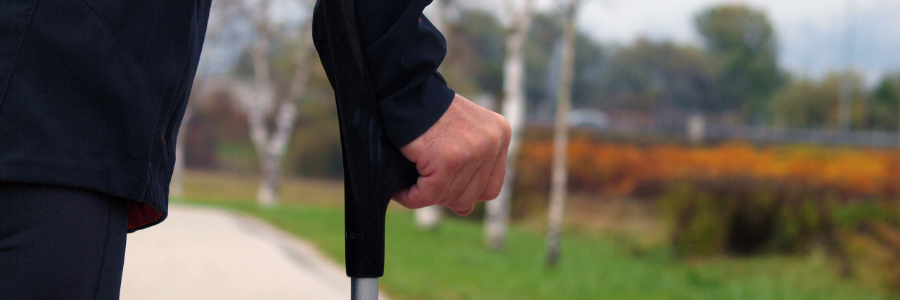 6 Tips for Accepting Your Rheumatoid Arthritis Diagnosis Man walking with a crutch outdoors on autumn day.