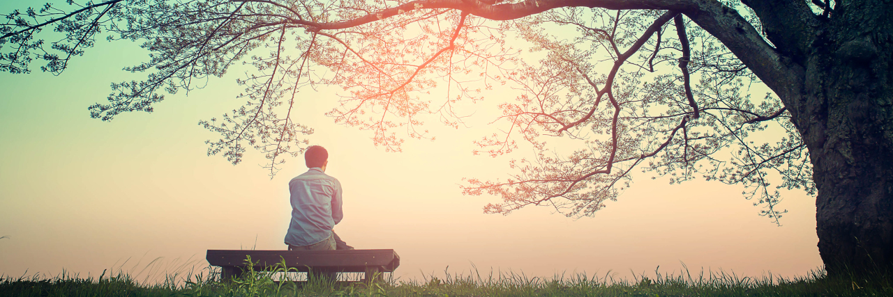 It's OK to Take a Break in Life With Rheumatoid Arthritis Man sitting on a bench under a tree.