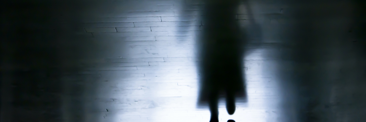Shadow of a woman walking in dark alley
