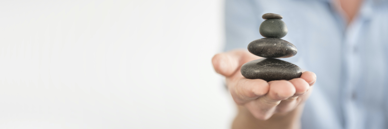 Coping With the Anger I Feel Towards My Chronic Illness Hand balancing rock tower on it
