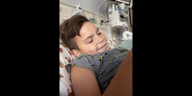 a boy smiling in his hospital bed