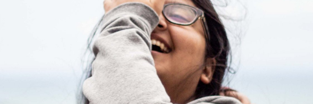 photo of the contributor laughing with their eyes closed, hand partially covering face