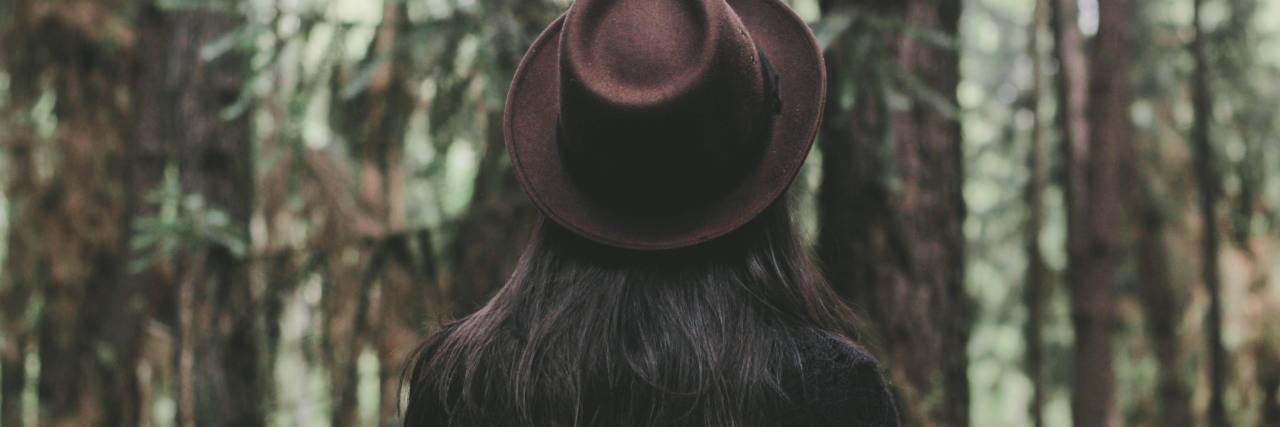 photo of a person with long hair and a hat looking away from the camera
