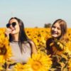 photo of three women in a field of sunflowers, laughing