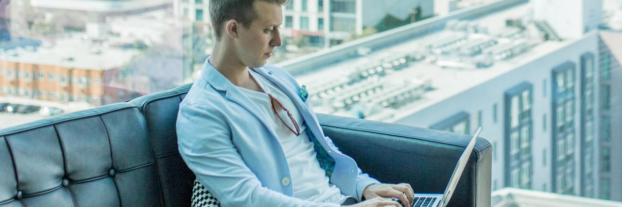 5 Signs You’re In a Toxic Job For Your Mental Health photo of a man working on a laptop in front of a cityscape window