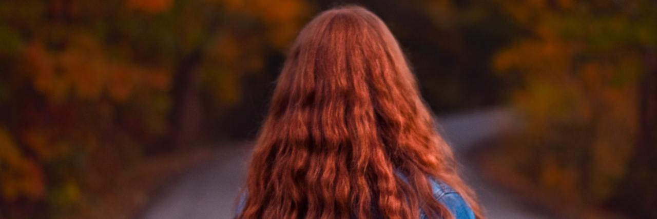 Coping With My Grief From Who I Was Before Mental Illness Back of a young woman walking outside during fall, long red hair