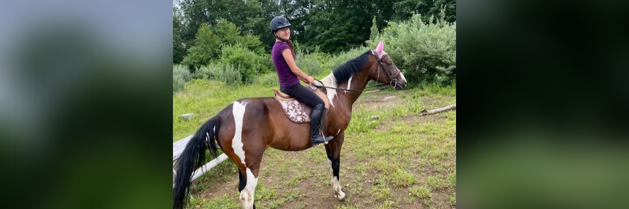 How Horses Heal Me on Hard Days as an Autistic Person Emily riding her brown and white paint horse.