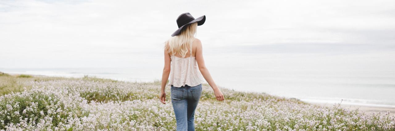 The Positives of Living With Borderline Personality Disorder A young white woman walking through a field of flowers looking behind her