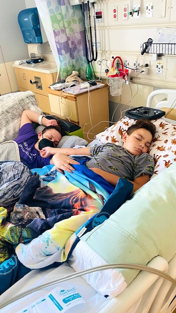 a mom laying with her terminally ill son in a hospital