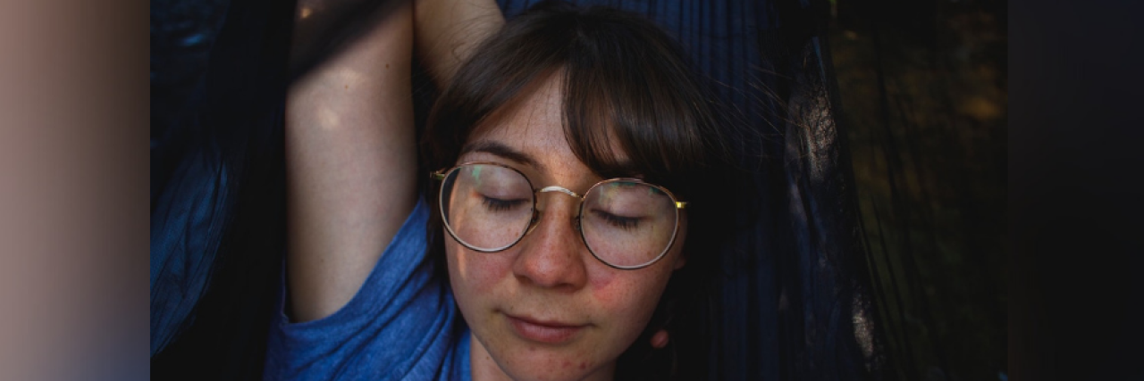 Young woman wearing glasses and laying with her eyes closed