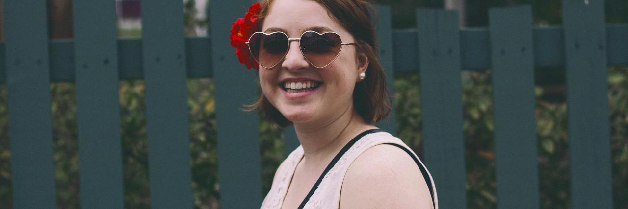 Why We Don't Need to Change the Term 'Borderline Personality Disorder' photo of a young woman smiling in front of a fence with a flower in her hair