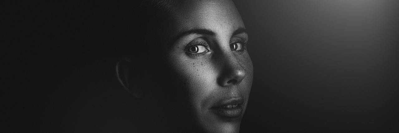 Black and white photo of a bald woman looking into the light, serious expression