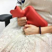 photo of a woman in a white dress clutching a red hot water bottle tight