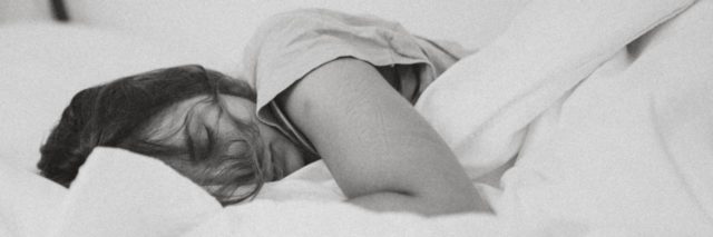 black and white photo of a woman lying in bed asleep