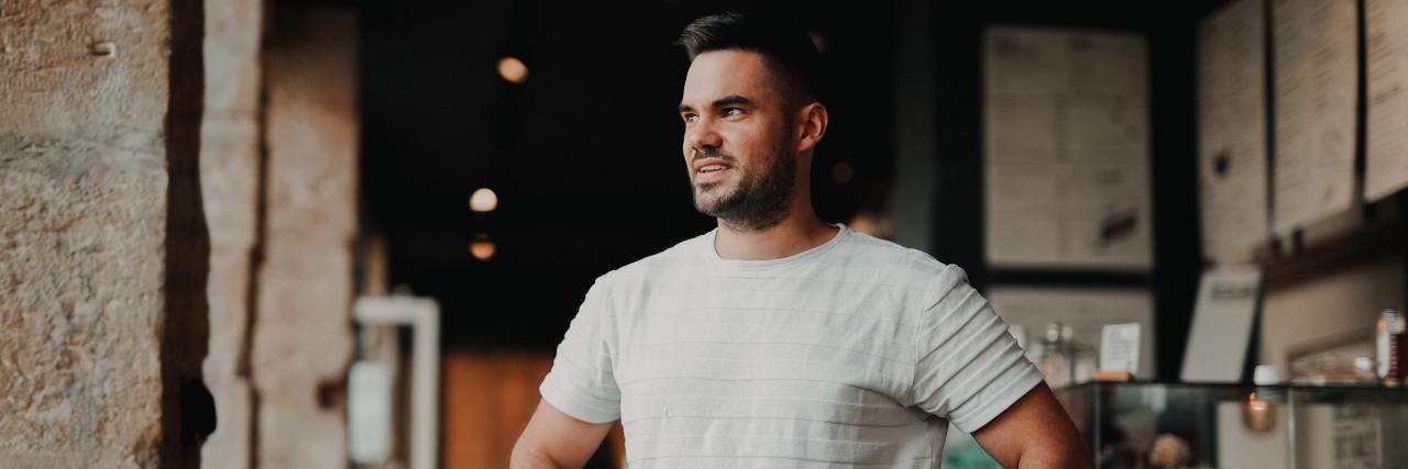 How Mental Health Advocacy Helps Me Bridge Gaps Young man standing in a cafe with his hands on his hips looking away confidently