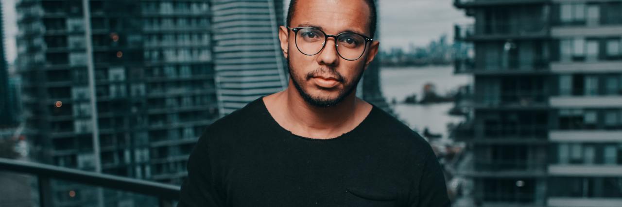 Advice for Job Searching With Bipolar Disorder photo of a man holding a mug in front of a window in a skyscraper, looking over a city