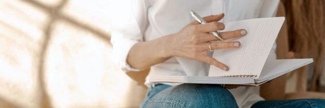 photo of a woman on a sofa writing notes in a notebook