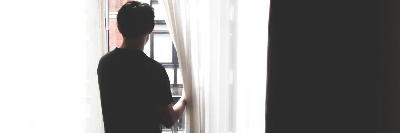 My Experience With Bipolar Disorder and Seasonal Affective Disorder photo of a man looking out of apartment windows