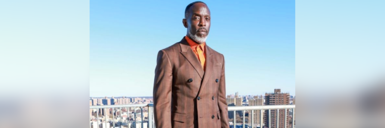 Actor Michael K. Williams standing on a roof deck in a suit