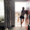 Photo of contributor standing in doorway and looking out of hotel room with her dog
