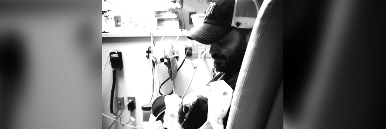 Black and white photo of Dad holding baby in NICU