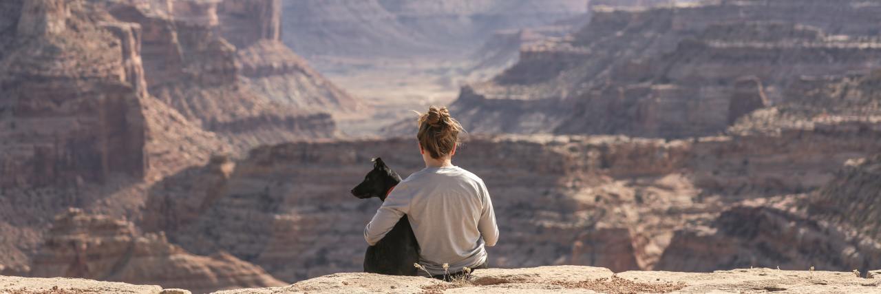 Life Without Depression: How I'm Embracing the Unknown Woman sitting on a cliff with her dog, overlooking beautiful landscape