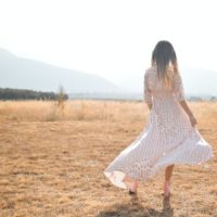 Back of a woman walking in a flowy summer dress outside