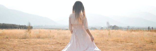 Back of a woman walking in a flowy summer dress outside