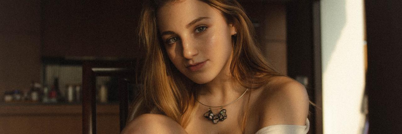 'Small' Wins That Are Actually Huge For People With Depression photo of a young woman sitting at home looking into camera with a small smile