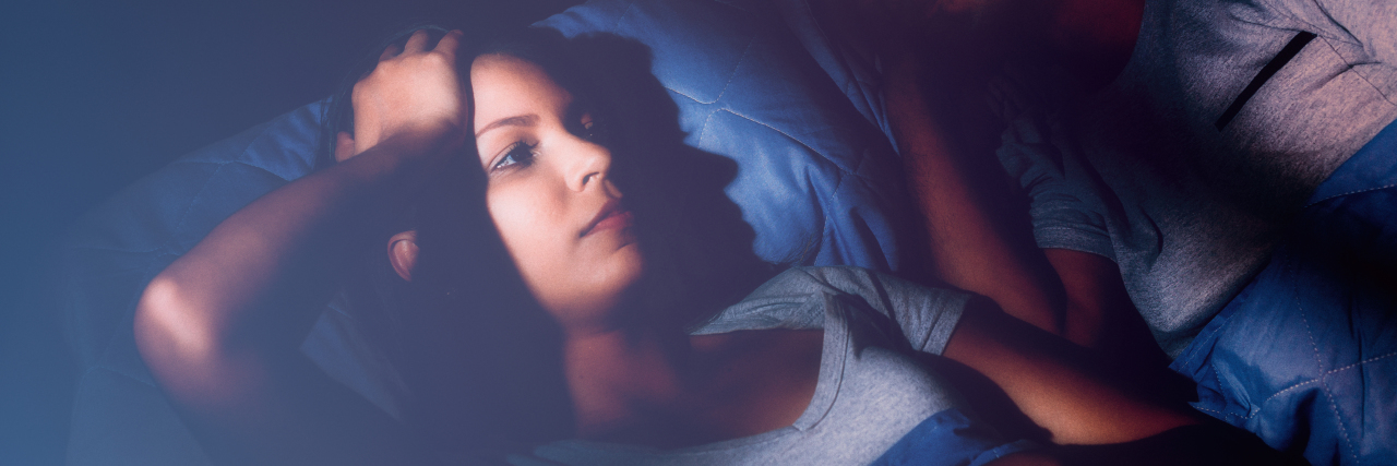 The Intrusive Thoughts That Loom Over Bedtime as a Cancer Patient Woman laying in bed next to her husband unable to sleep.