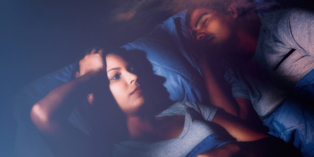 The Intrusive Thoughts That Loom Over Bedtime as a Cancer Patient Woman laying in bed next to her husband unable to sleep.
