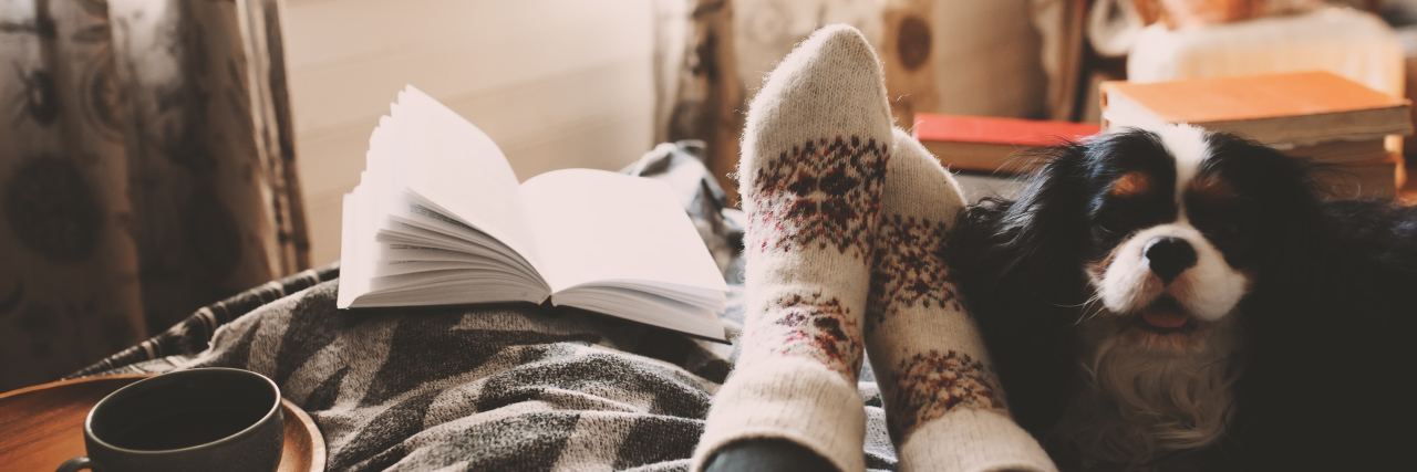 Cozy winter day: A woman with fibromyalgia at home during cold weather wearing fuzzy socks and drinking tea.