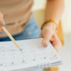 Woman marking dates on calendar.