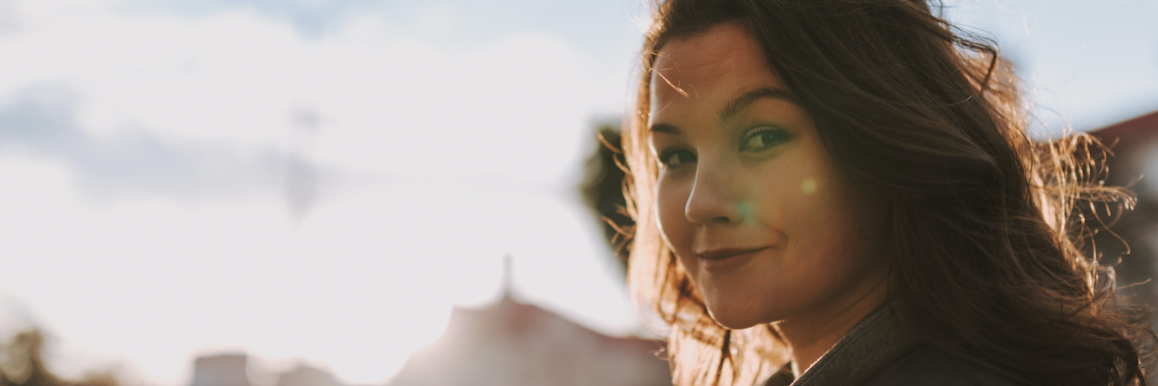 Sharing the Same Hypothyroidism Diagnosis as Those in My Family Woman gently smiling in front of city background on a sunny day