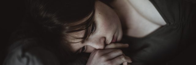 Close-up of sad woman lying on bed