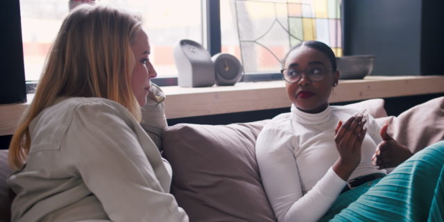 Friends sitting on a sofa talking.