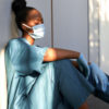 Exhausted female Black nurse wearing face mask.