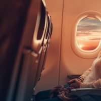 Young woman sitting in an airplane looking out the window