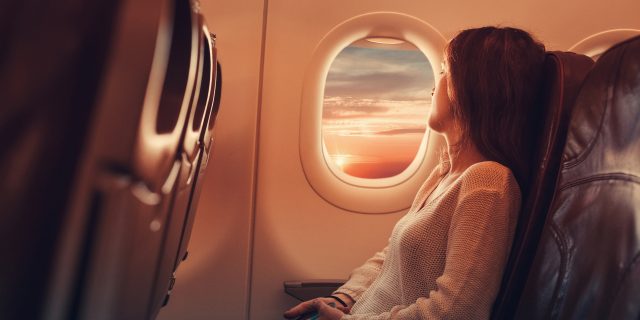 Young woman sitting in an airplane looking out the window