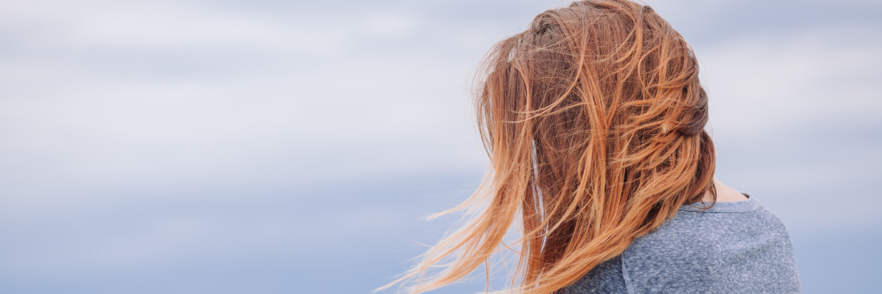 I'm Sorry to the Person I Hurt Due to Borderline Personality Disorder Woman in a t-shirt standing by the ocean with her red hair blowing across her face