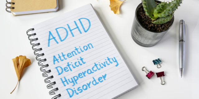 ADHD Attention Deficit Hyperactivity Disorder written in notebook on table.