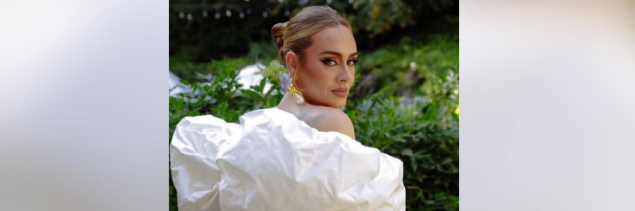 Photo of Adele wearing dress with white sleeves and looking back over her shoulder