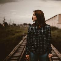 Woman standing on train tracks looking over to the side