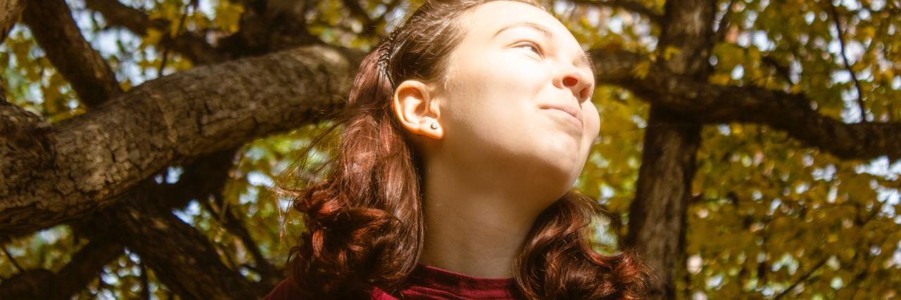 What 'You're So Strong' Means When You Have Depression photo of a woman taken from below with tree overhead, she's looking off to the distance with eyes squinted against sun