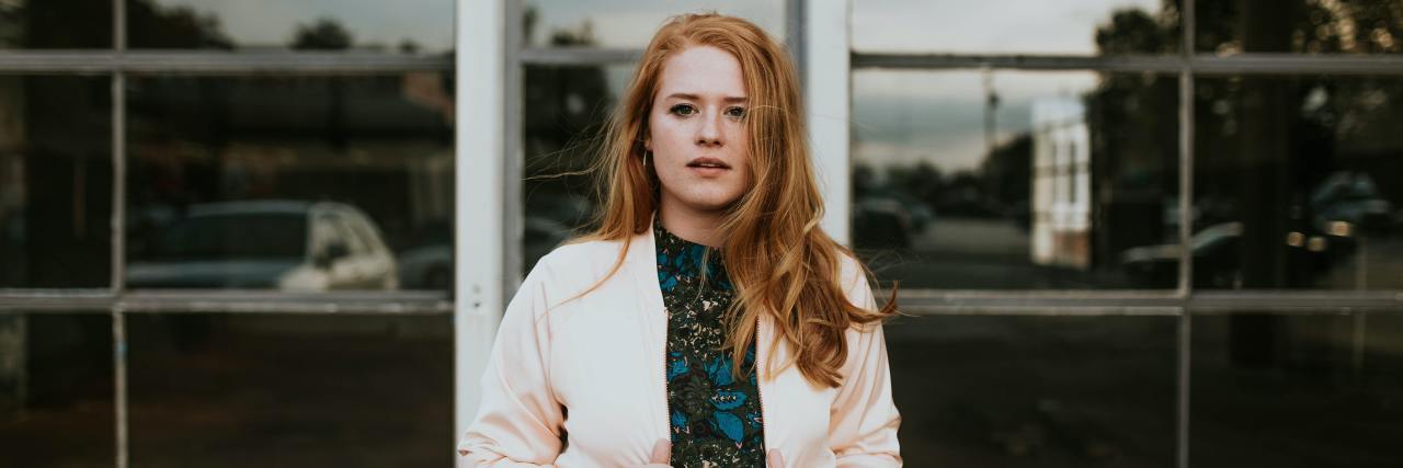 Electroconvulsive Therapy Saved My Life, Even If It Caused Memory Loss Young woman in a dress and cardigan standing outside, contemplative expression