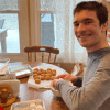 Dominic at the kitchen table smiling and making baked goods