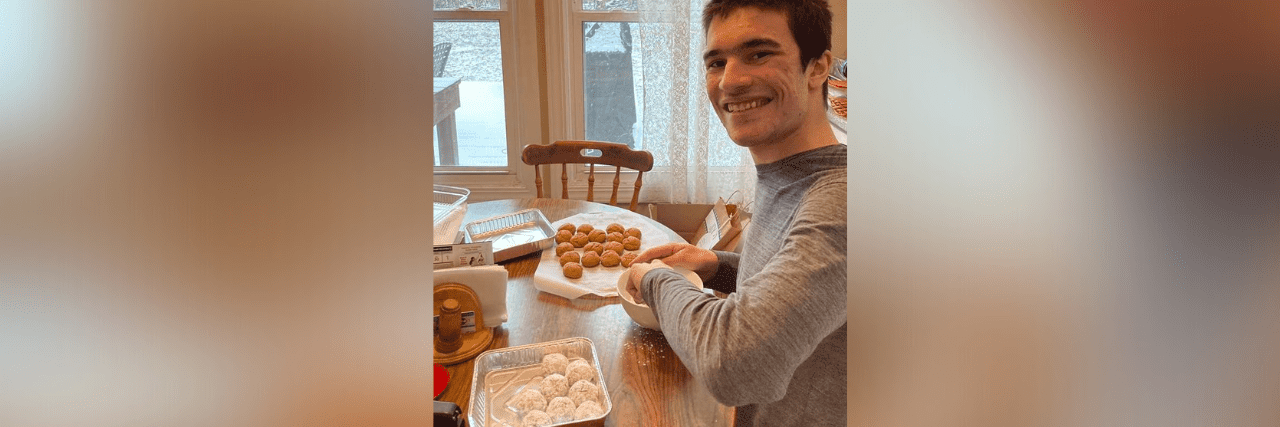 Dominic at the kitchen table smiling and making baked goods